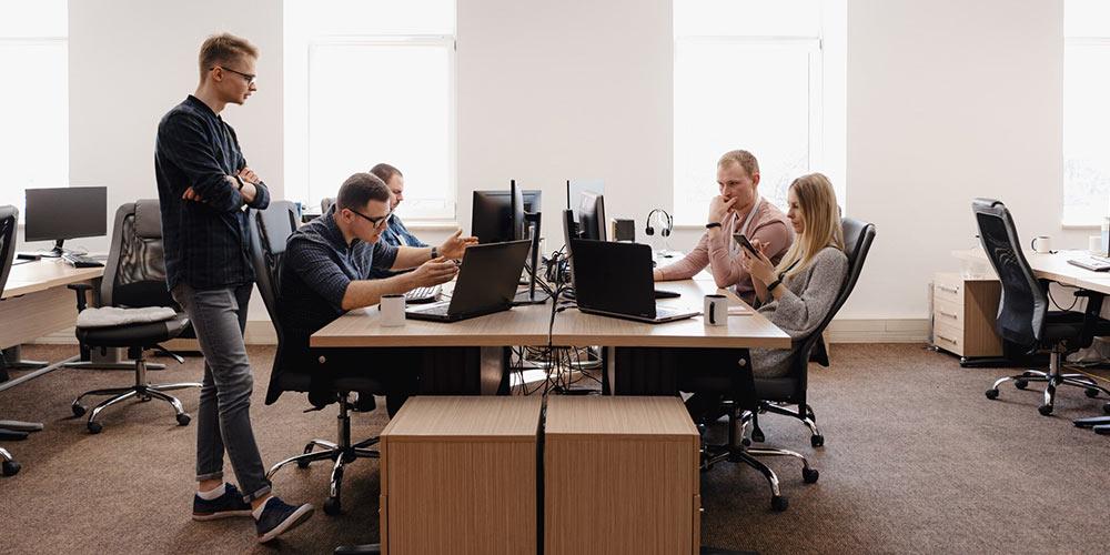 People working in a shared office space where background noise can affect video call clarity